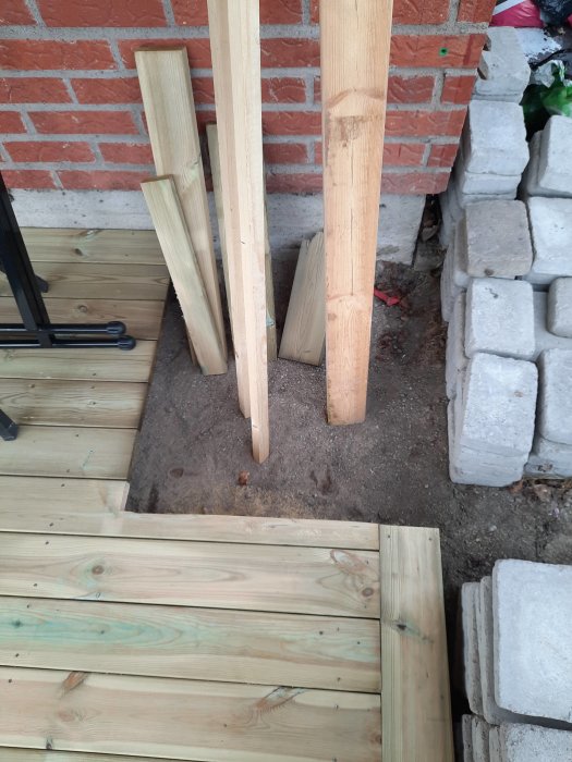 Nylagd trall bredvid en tegelmur, med några träplankor stående och minimalt spillmaterial intill.