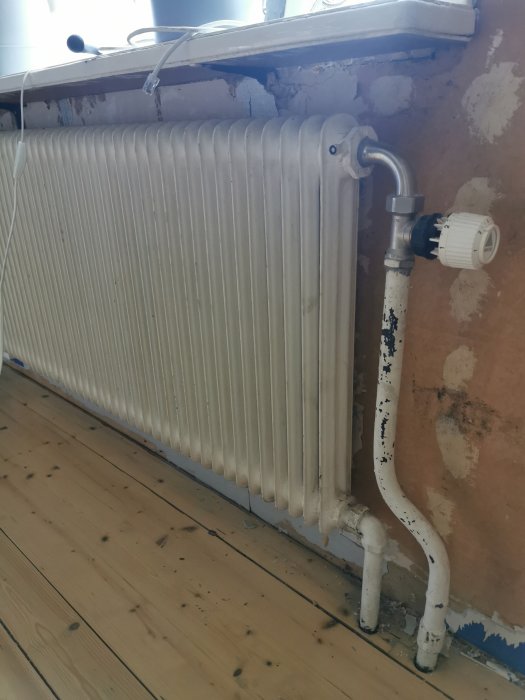 Ett gammalt element monterat på vägg, behov av demontering inför rummets renovering.