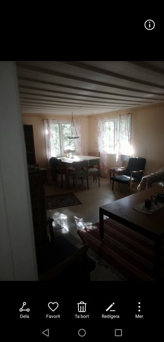 Interiör av sommarstuga med befintligt mindre fönster, matbord och stolar.