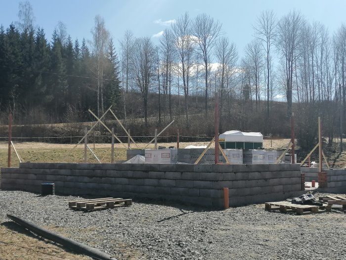 Grunden till ett hus med det sjätte lagret av betongblock, byggnadsmaterial och stöttor i bakgrunden.