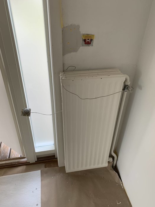 Väggmonterad, äldre Honeywell termostat kopplad med koppartråd till radiator i renoverat hus från 1965.