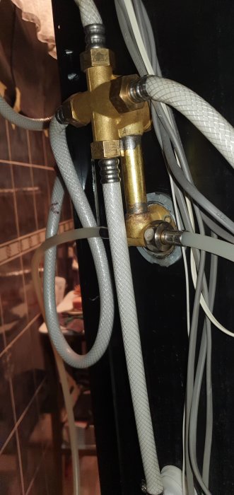 Duschblandare med synliga rör och kopplingar i en teknisk miljö, fråga om byte av patron.