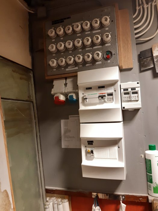 Gammal och ny elcentral på en vägg med säkringsdosor och automatsäkringar.