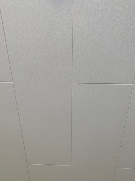 Vit fabriksmålad takbeklädnad med tydliga skarvar, möjligtvis av gipsmaterial.