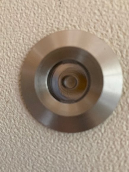 Närbild på en rund, metallisk byggdetalj utan synlig beteckning monterad på en vägg.