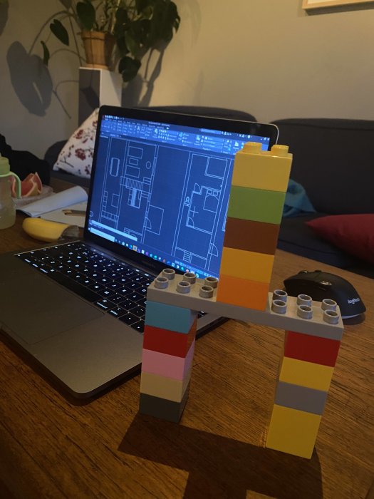 Ritningsprogram öppet på en bärbar dator med en färgglad LEGO-konstruktion framför på ett bord.