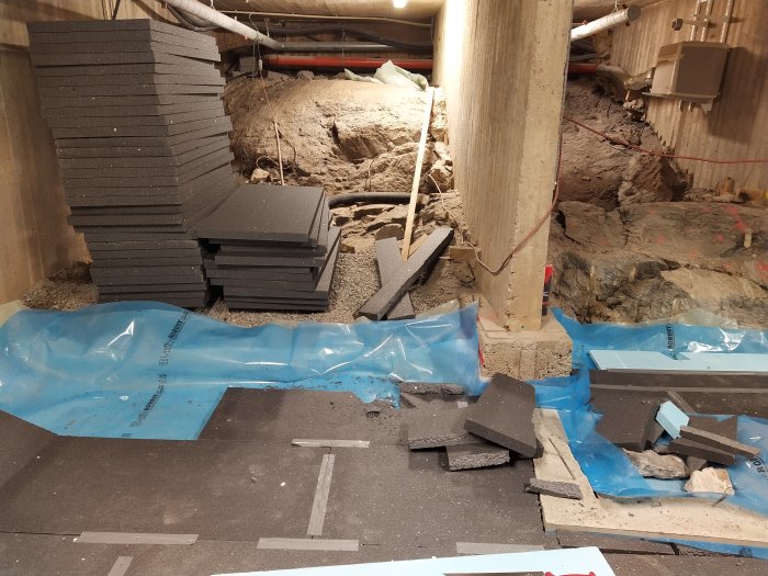 Byggplats med ojämnt underlag och cellplaststycken över ojämna grus och bergsytor.