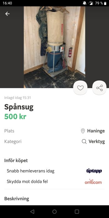 En begagnad spånsug i ett rum med träväggar och svarta kakelplattor på golvet.