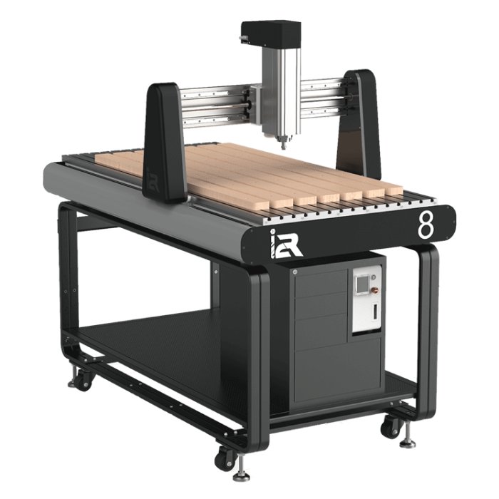CNC-maskin modell i2R-8 med arbetsbord och fräsmonterad över trämaterial, ämnat för snickeri och borrning.