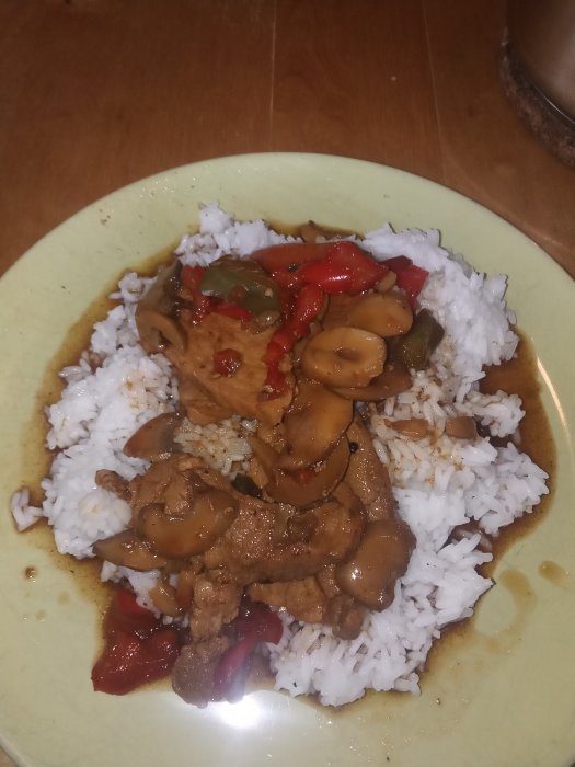 En tallrik med kotlettrad, champinjoner, paprika och ris.