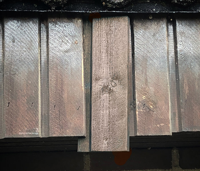 Nymålade och gamla panelbrädor på husvägg, skillnad i glans och färgton synlig.
