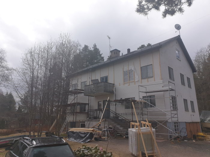 Renoveringsarbete på en tvåvånings villa med byggnadsställningar och oavslutad fasad.