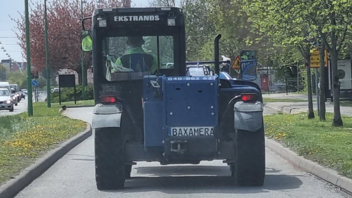 Blå traktorliknande fordon på en gata med registreringsskylt "BAXAMERA".