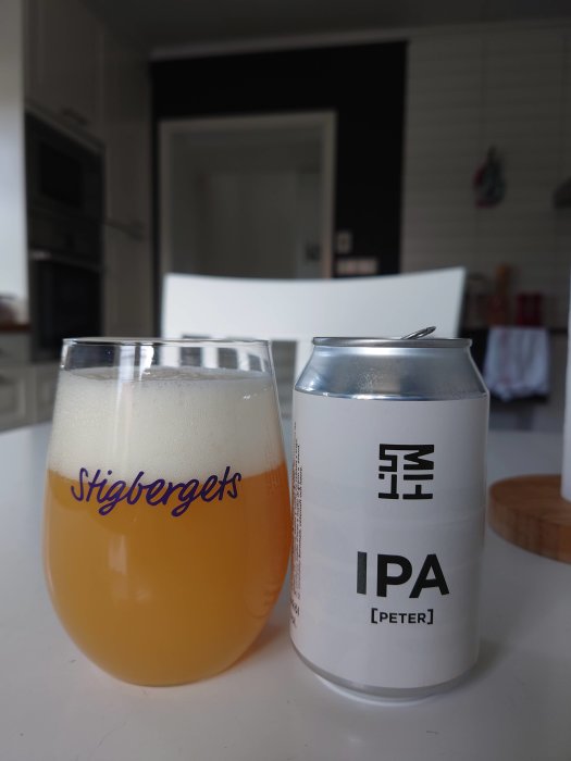 Glaset med öl och burk med etiketten "IPA" på ett vitt köksbord.