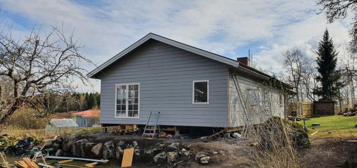 Nyisolerat hus med nymonterade fönster och dörrar, byggmaterial framför.