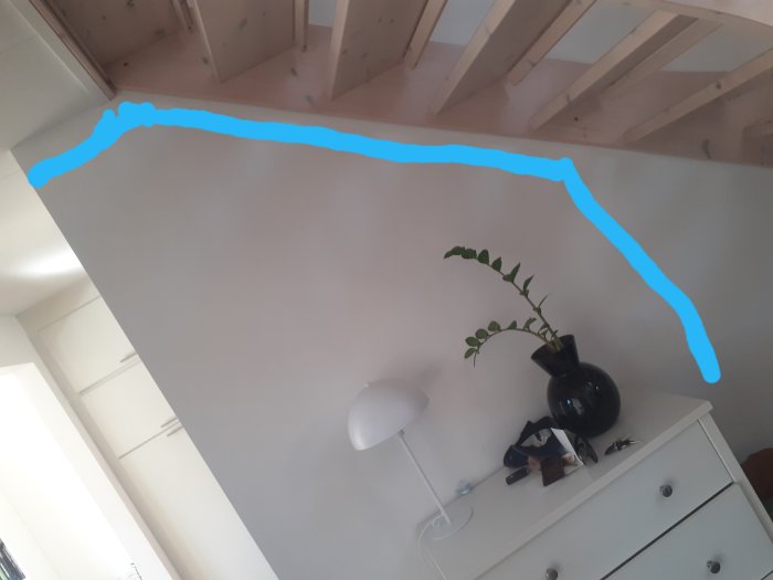 Interiör med takbjälkar och en vägg markerad med blå linjer för planerad nedtagning.