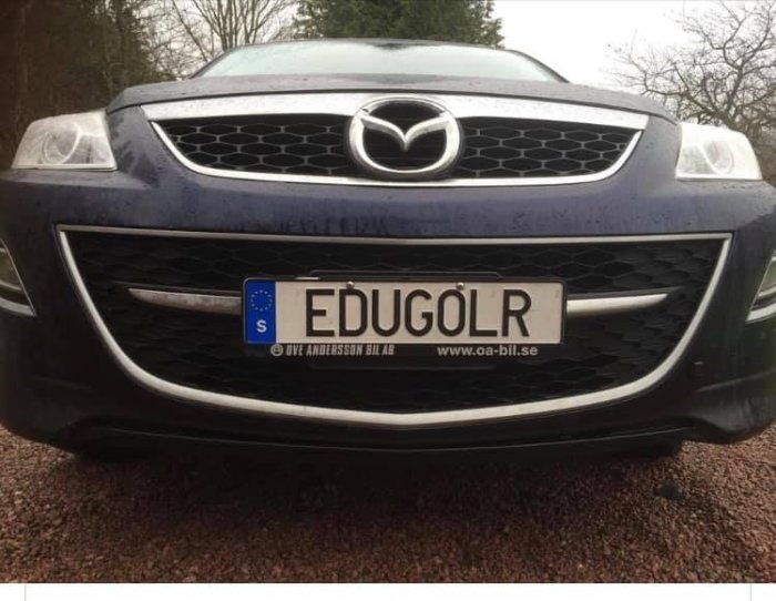 Främre delen av en blå Mazda-bil med svensk registreringsskylt som visar texten 'EDUGÖLR'.