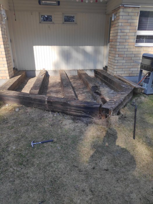 Gamla, borttagna slipers på gräsmatta framför hus, kvar efter renoveringsprojekt.