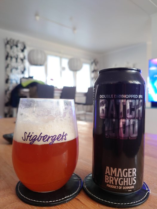 Ett glas öl och en burk Batch 1000 från Amager Bryghus på ett bord i ett vardagsrum.