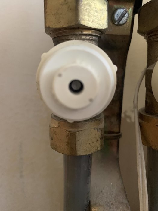 Närbild av ett radiatorställdon monterat på en ventil med metallpip.