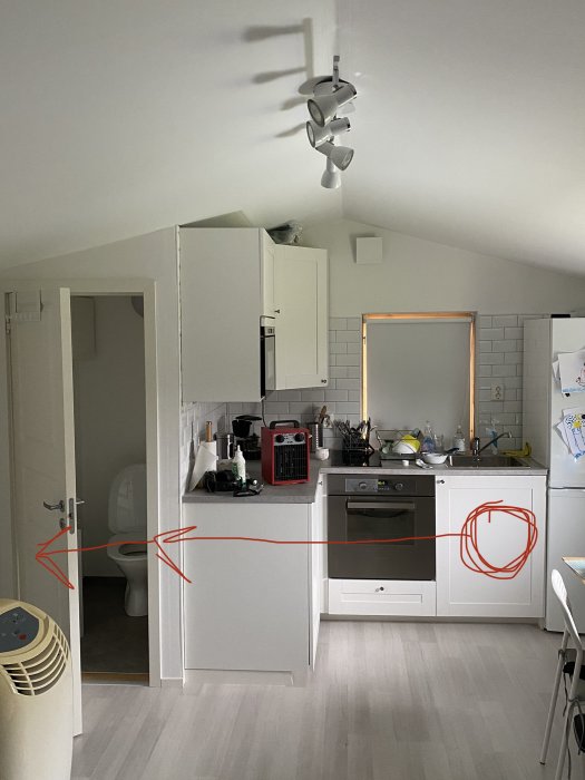 Interiörbild av ett kök med markerade vägar för vattenrör från under köksvasken till toaletten.