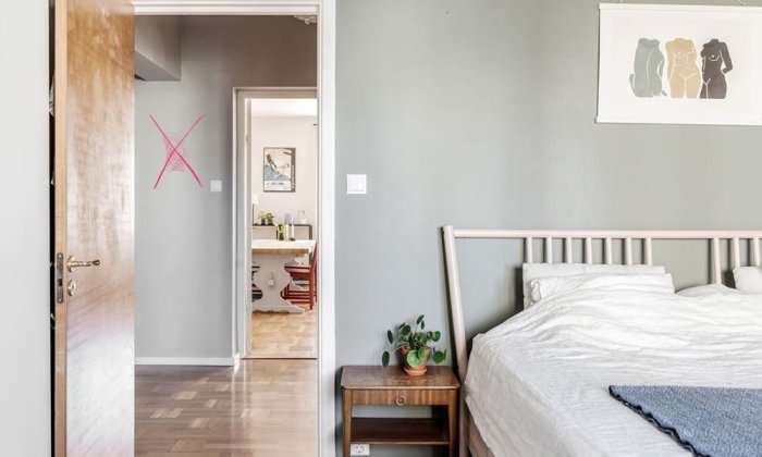 Vy från ett sovrum mot en markerad vägg med ett kryss, som illustrerar en frågeställning om att riva väggen för att öppna upp rummet.
