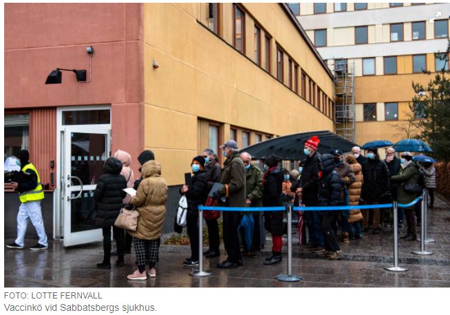 Kö av människor för vaccinering utanför Sabbatsbergs sjukhus, vissa med munskydd felaktigt under hakan.