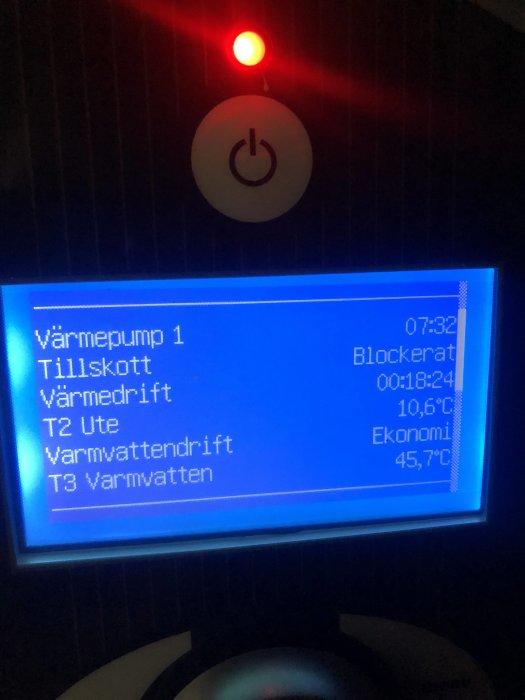 Värmepumpens kontrollpanel visar temperaturer och status med en röd indikatorlampa tänd.