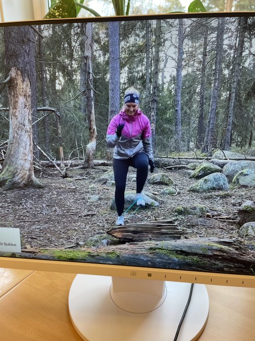 Bild på skärm som visar person som balanserar på trädstam i skogsmiljö.