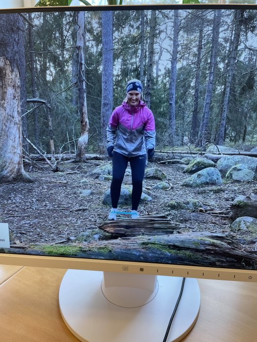 En bildskärm som visar en person som står i skogen på en sned och uppstagad bärlina.