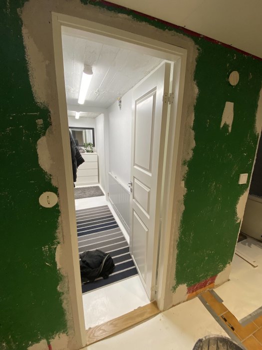 Utsikt genom en dörrkarm med spacklade kanter i ett renoveringsprojekt.
