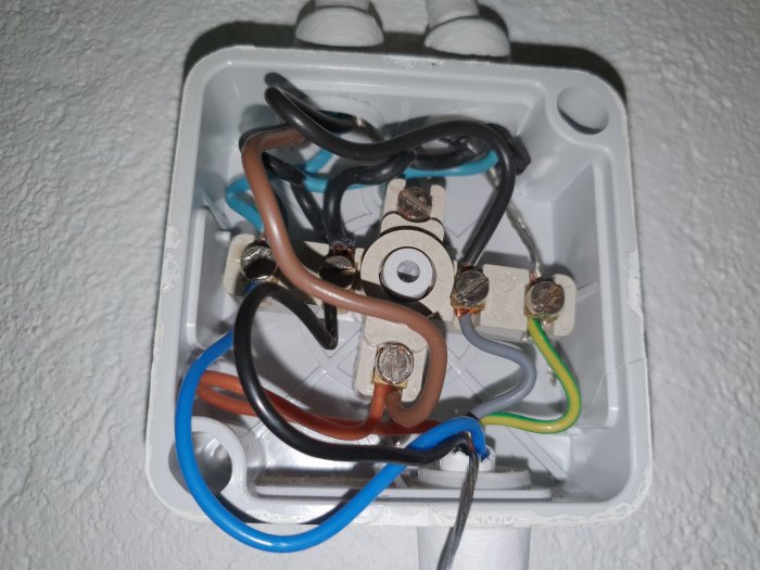 Elektrisk dosa med oordnade kablar och en kopplad strömbrytare, installationsfel misstänks.