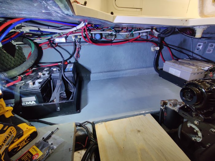 Båtens motorrum med ordnad elinstallation och nya batterier monterade, verktyg på golvet.