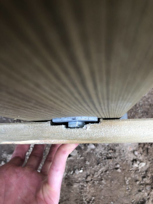 Hand håller träbit med precisionsspår fräst för metallbeslag, resultat av använd överhandsfräs.