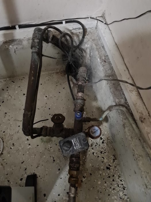 Slitna vattenledningar och anslutningar i en betonggrop, vilket kan vara orsak till luftproblem i tappvatten.
