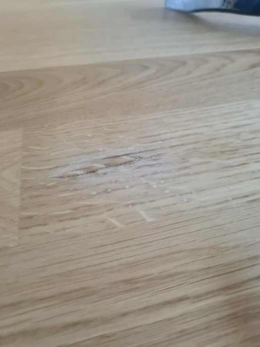 Slipat trägolv med synlig reparation och limrester, slipat område ljusare än resten av golvet.