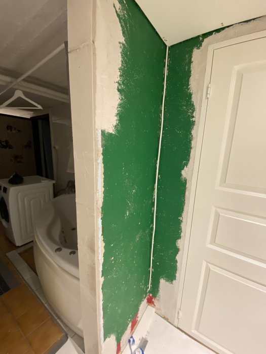 Vägg i renoveringsfas där en kabel har bilats in för en dold installation med synlig grönt färgskikt.