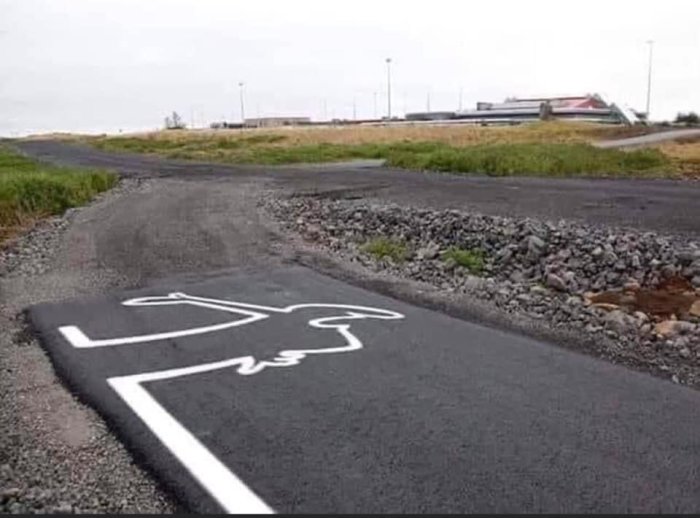 Cykelväg med en konstig målning som liknar en cyklist krockad från sidan, vid en vägklyvning.