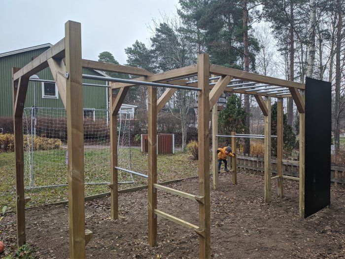 Träkonstruktion för utomhusprojekt med pelare och tvärbalkar under uppbyggnad i en trädgård.