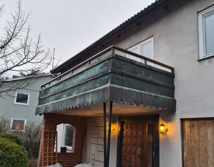 1950-tals hus med sliten balkong som behöver renovering, synlig betong och kopparräcke.