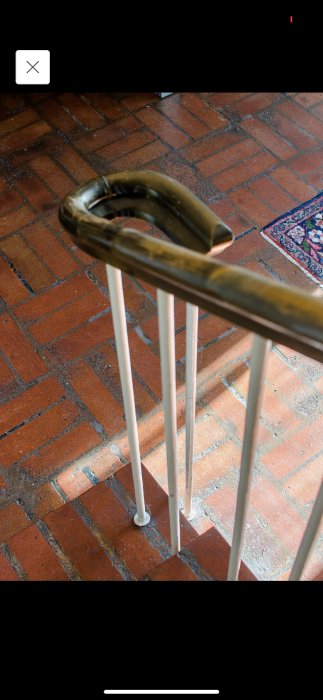 Gammalt tegelgolv i behov av underhåll med synliga fogar och del av trappräcke.