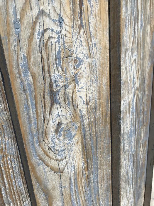 Träyta på garage med flagande linoljefärg och synliga träådror.