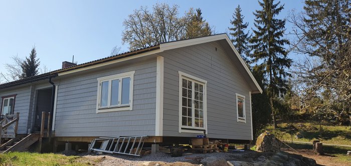 Fasad med nymonterade foder och knutbrädor runt fönster och dörrar på ett hus under renovering.