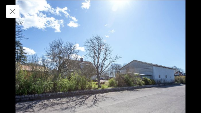 Utsikt över ett nyköpt hus med stort garage, omgivet av grönska och under en klarblå himmel.