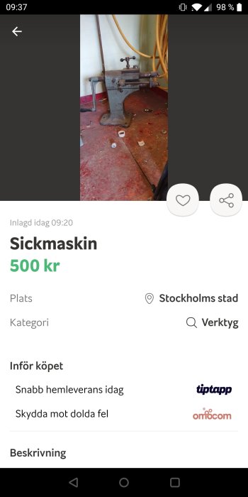 Gammal sickmaskin i metall på röd smutsig verkstadsgolv med gula slangar i bakgrunden.