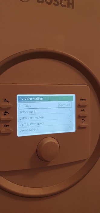Display på en värmepump med meny för varmvatteninställningar, visar driftläge 'Komfort'.