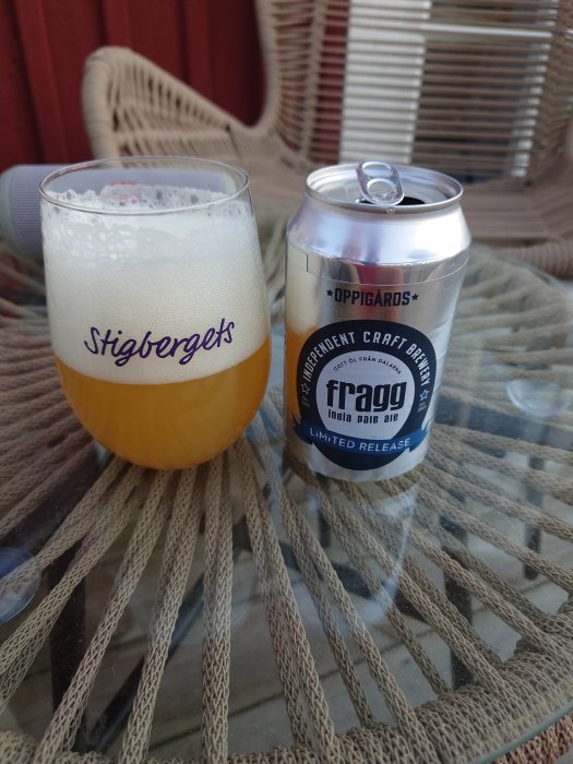 Ölglas fyllt med hazy ale märkt "Stigbergets" och en Oppigårds "frägg" India Pale Ale burk på ett bord.