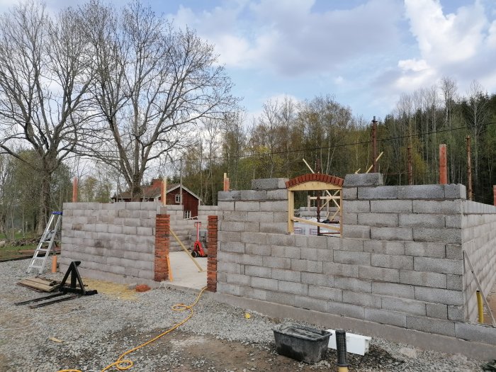 En pågående byggplats med den första bågen konstruerad ovanpå en mur av betongblock.