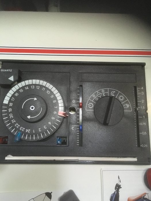 Närbild av en analog termostat med rattar och temperaturskalor.