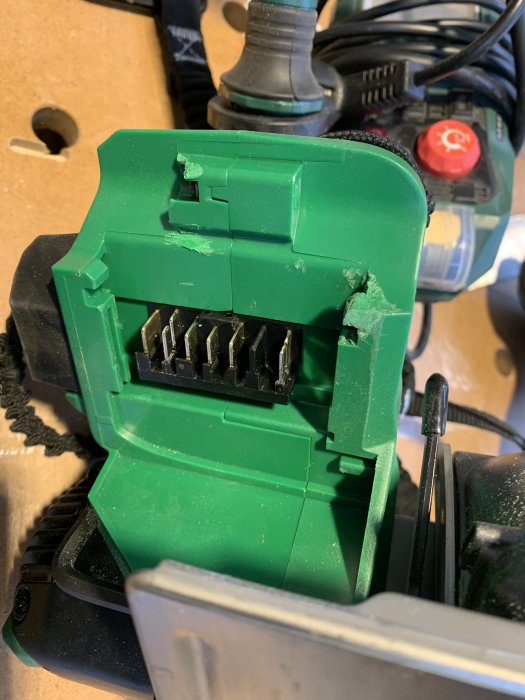Skadat batterifäste på en grön Hikoki cirkelsåg med en avbruten plastpinne.